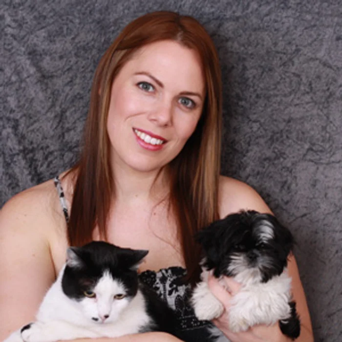 Carrie, certified master groomer, holding a cat and a small dog